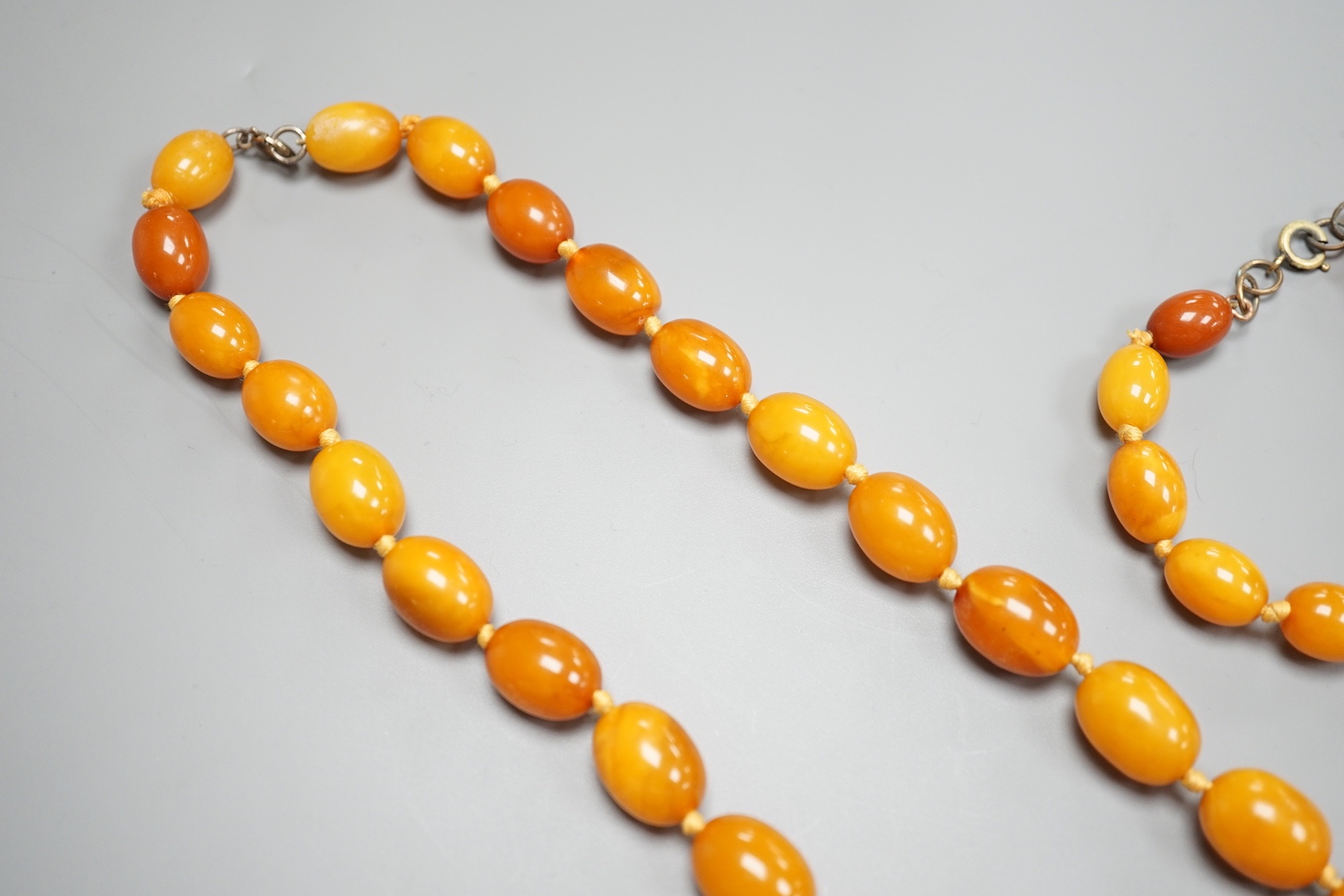 A single strand graduated oval amber bead necklace, 65cm and a similar bracelet, 18cm, gross weight 82 grams.